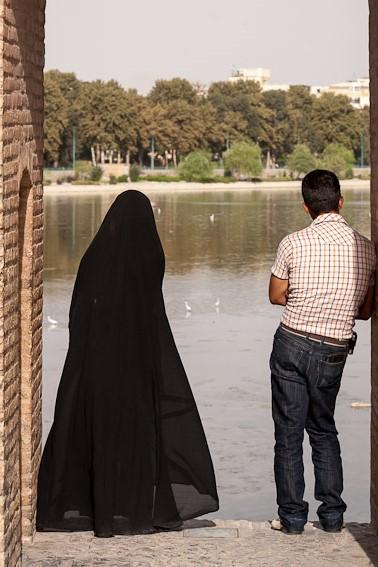 An Iranian Man And Woman Standing In An Archway On Si-o-se Pol Bridge Look Over The Zayandeh River In Isfahan, Iran On August 4, 2008. The Woman Is Wearing A Chador, And The Man Is Wearing Pants And A Short Sleeve Shirt. Si-o-se Pol Bridge, Which Means "33 Bridge" Or The "Bridge Of 33 Arches", Is One Of Isfahan's Most Famous Landmarks. It Was Commissioned In 1602 By Shah Abbas I.