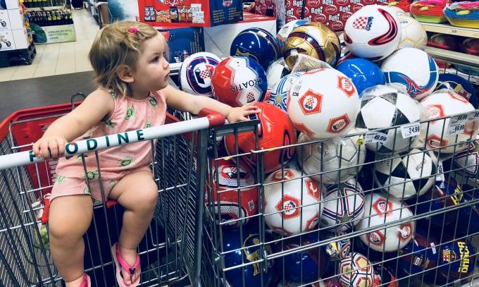 Pieni tyttö katsoo palloja kaupassa.