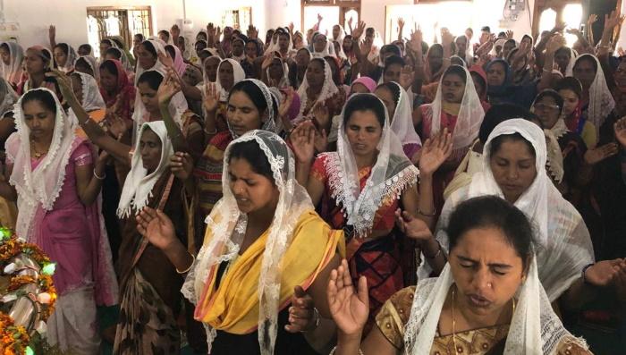 Intialaiset naiset ylistävät kirkossa.