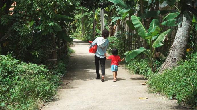 Nainen ja lapsi kävelevät tiellä Indonesiassa.