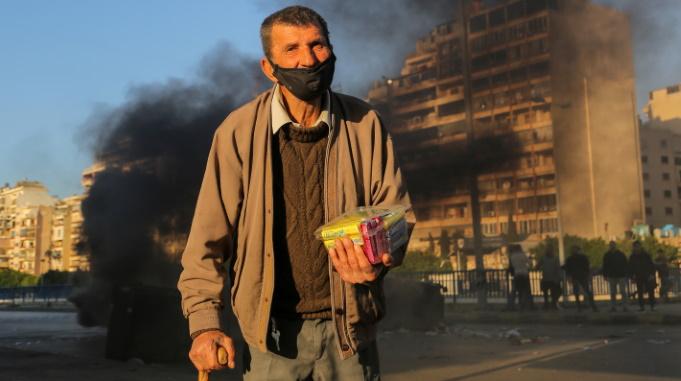 Iäkäs köyhä mies ja savuava katu Libanonissa.