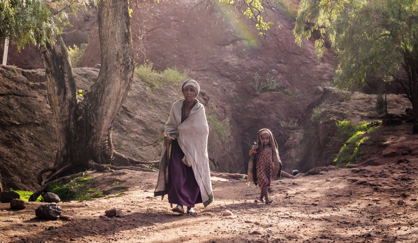 Etiopialainen nainen ja lapsi kävelevät paljasjaloin.