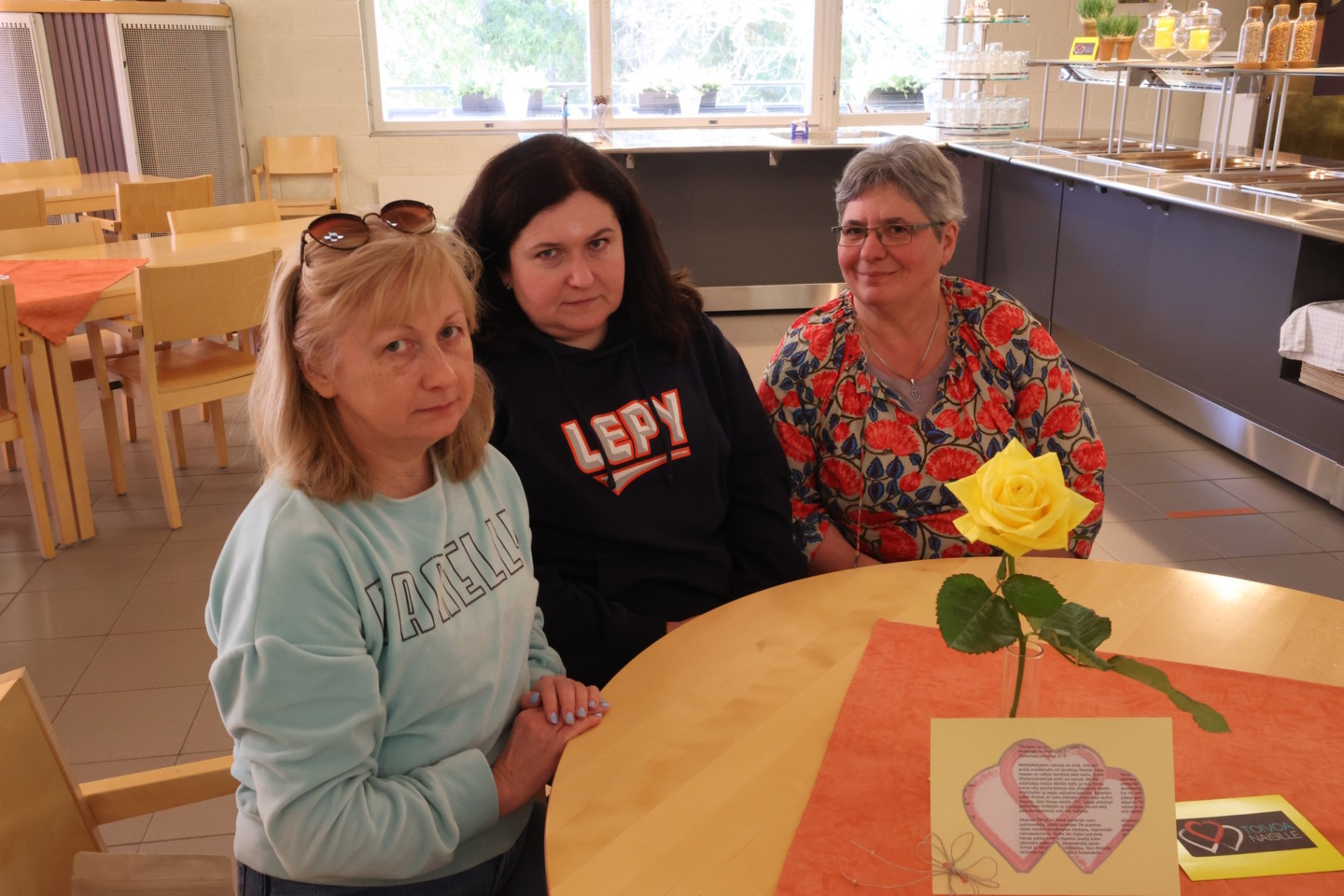 Kolme naista, ukrainalaiset Hanna ja Tanja sekä ranskalaistaustainen Christine Marc istuvat pöydän ääressä.