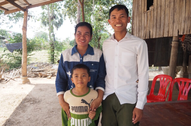Perheseminaariin osallistunut aviopari ja heidän poikansa kambodžalaisen talon edustalla.